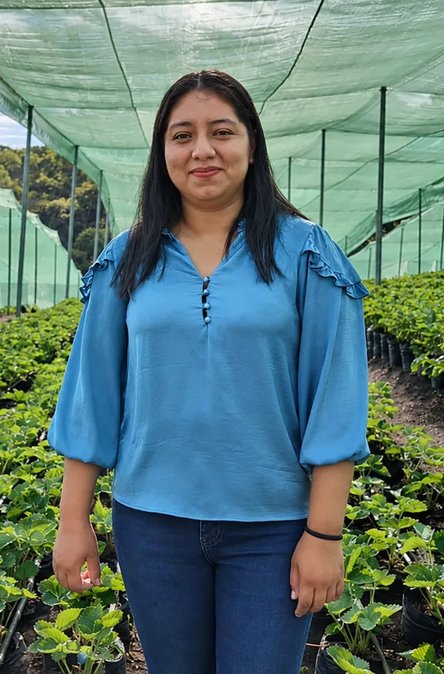 Productora joven con blusa celeste sonríe entre los surcos